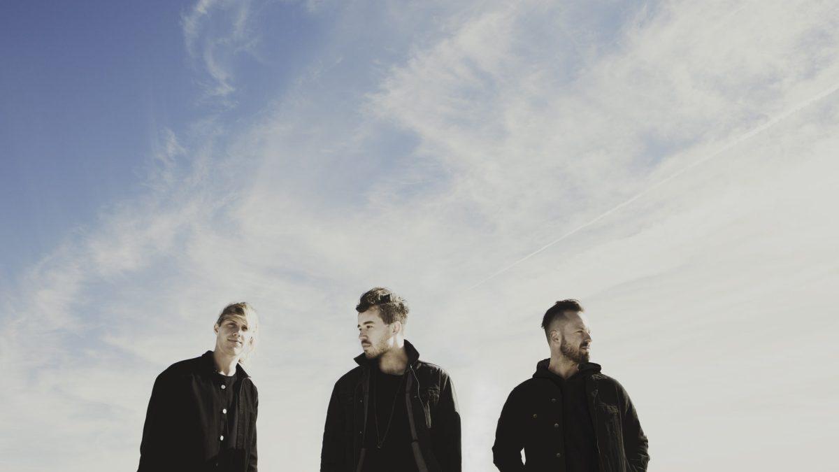 All members of Rufus Del Sol standing under a clear sky.